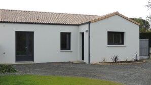 A modern single-story building with a tiled roof, a front door, and two windows. - Maison à 15 Minutes de la mer (Saint-Urbain)