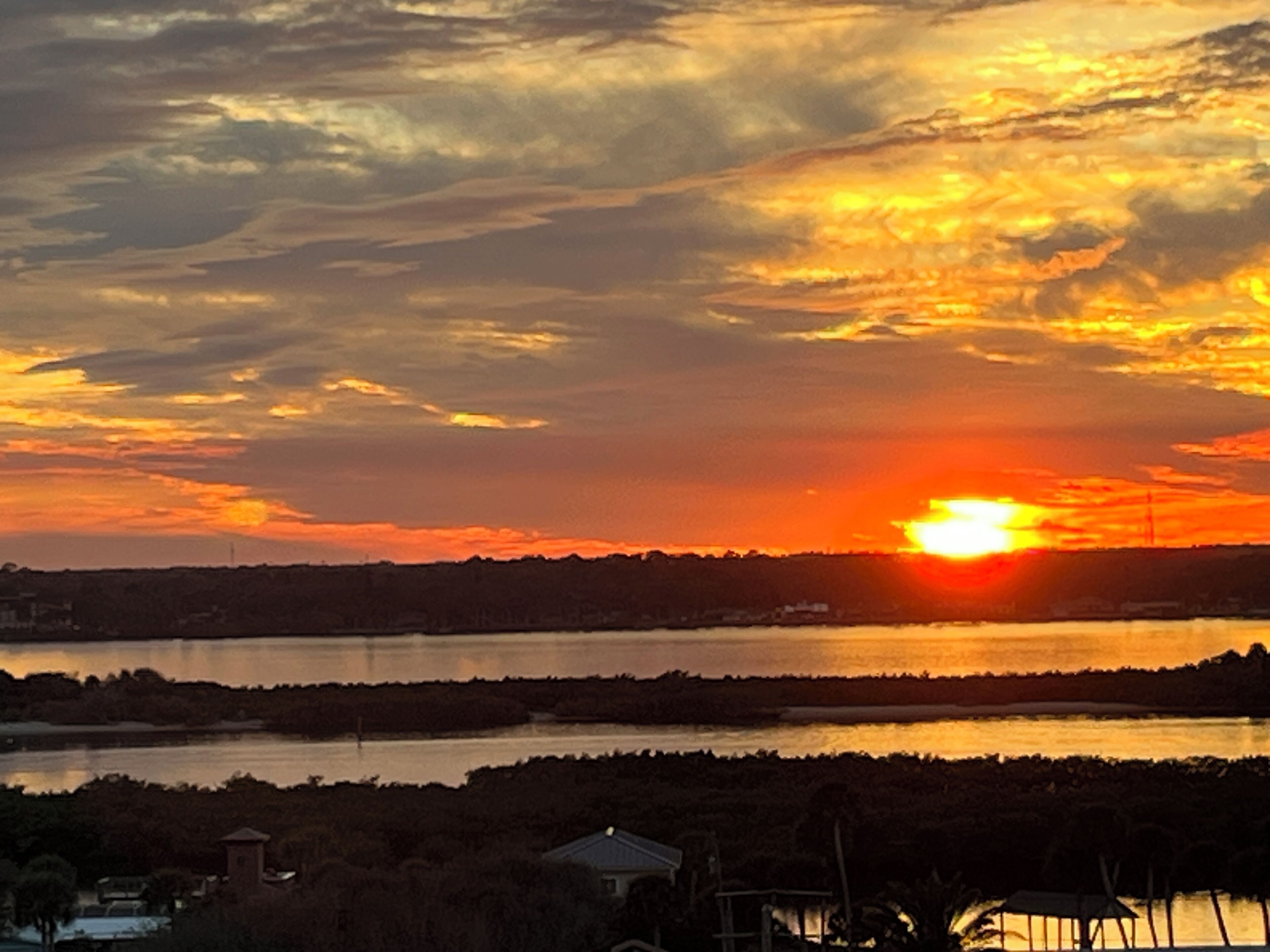 A sunset over a body of water with a distant shoreline and buildings.