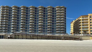 Een hoog hotel met meerdere balkons en uitzicht op het strand.