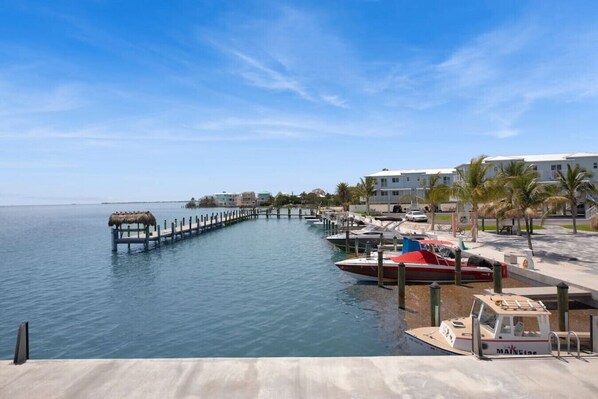 A marina with boats docked, a pier extending into the water, and buildings in the background. - Oceanside Spacious Studio Escape (Marathon)