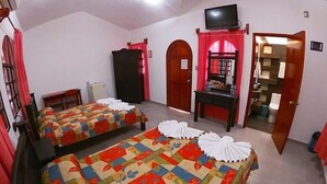A hotel room with two beds, a TV, a desk, and a bathroom visible through an open door. - Hotel Casa Kolping (Tuxtla Gutierrez)
