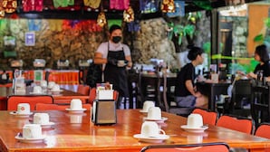 A restaurant with wooden tables and red chairs, a stone wall, and colorful decorations. - Hotel Casa Kolping (Tuxtla Gutierrez)