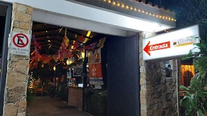 A hotel entrance with a stone pillar, a no parking sign, and an entrance sign pointing left. - Hotel Casa Kolping (Tuxtla Gutierrez)