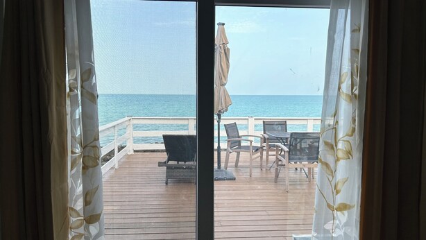 A deck with outdoor seating and a view of the ocean.