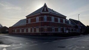 En rød murbygning med saddeltag og mange vinduer.