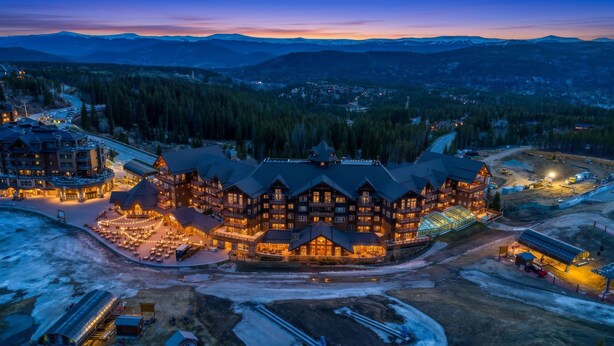 A large lodge with multiple stories, a ski lift, and a dining area with outdoor seating.