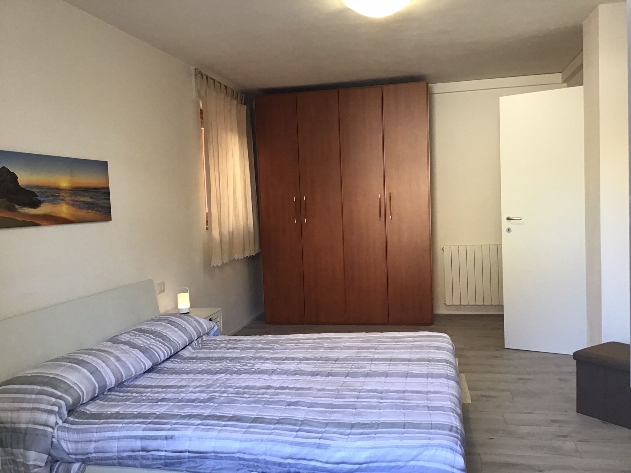 Une chambre à coucher avec un lit, une armoire, un tableau et un radiateur.