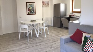 Ett kompakt bostadsutrymme med en matplats, ett litet kök och en soffa.