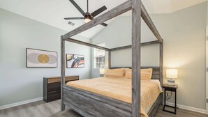 A four-poster canopy bed with a wooden finish, a ceiling fan, and two bedside tables with lamps. - Prime Downtown Cornelius Townhome (Cornelius)