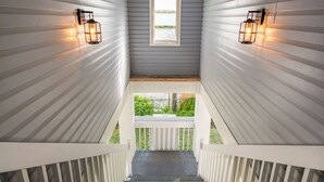 Eine Treppe führt zu einem Balkon mit grauen Wänden und zwei Wandleuchten.