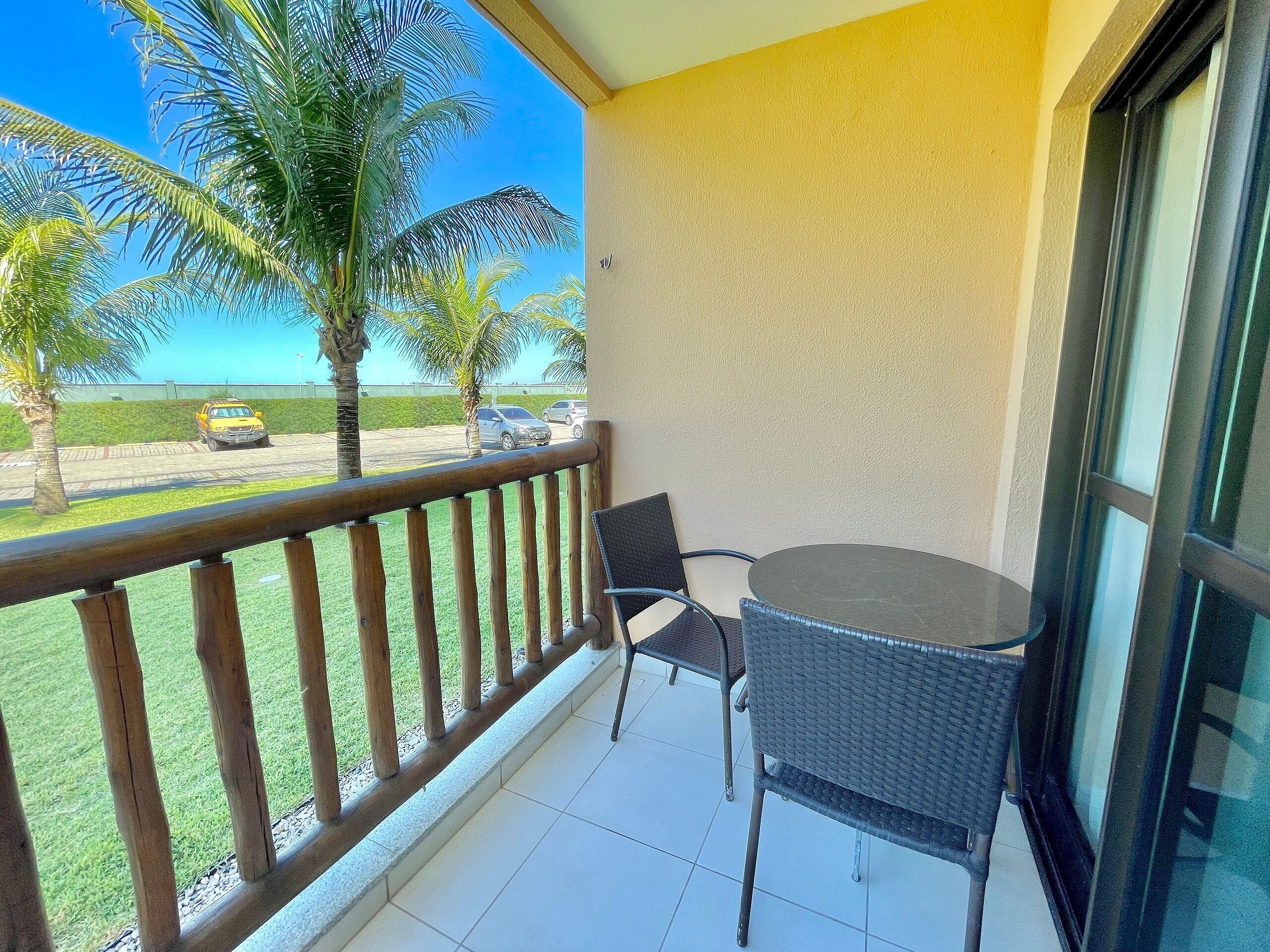 A balcony with a view of palm trees and a parking lot.