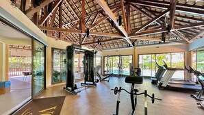 A gym with exercise equipment, large windows, and a wooden ceiling. - Incrível Resort VG Sun (Caucaia)