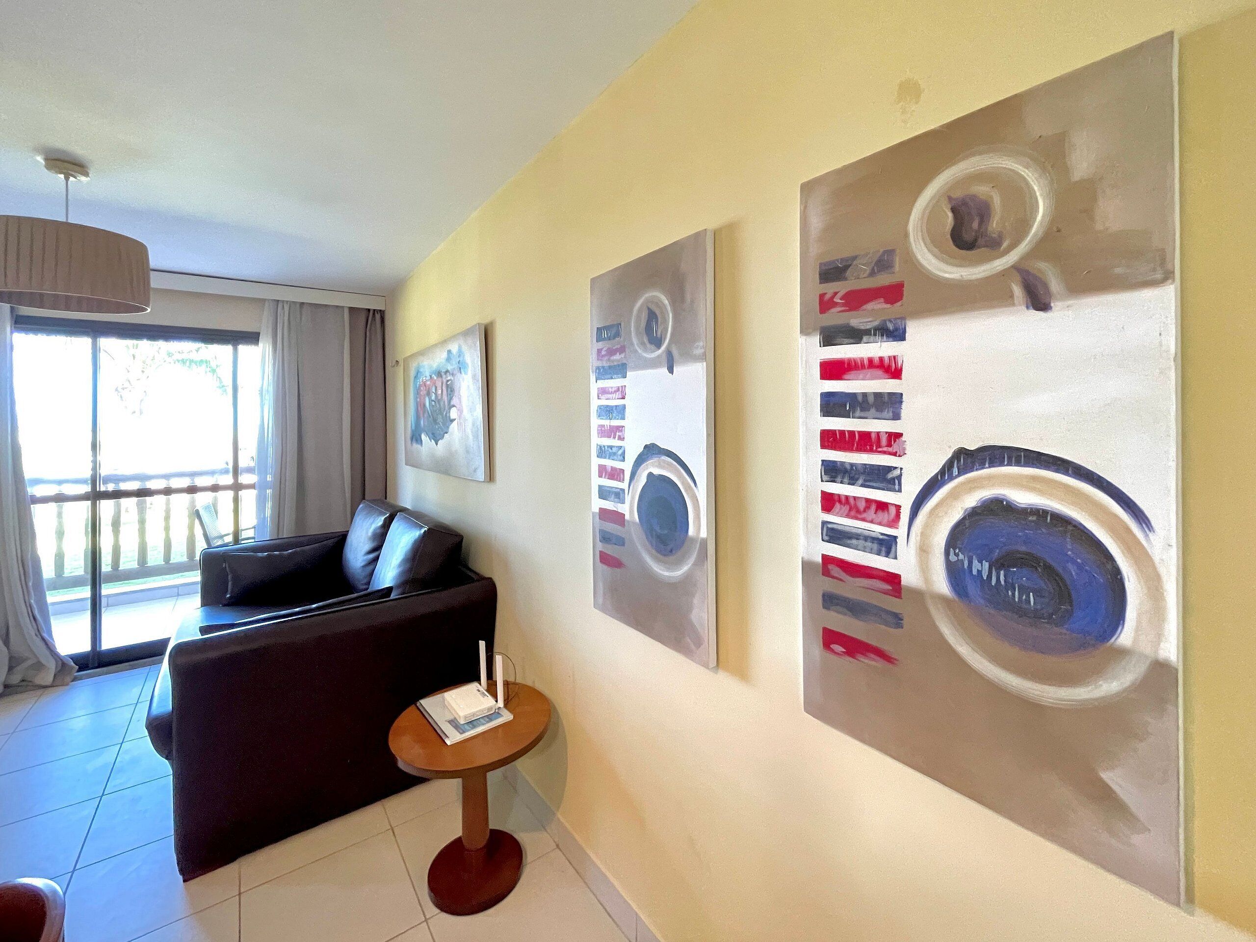 A modern living room with a sofa, a small round table, and abstract wall art.