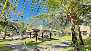 A well-maintained outdoor area with palm trees, a gazebo, and a paved walkway. - Incrível Resort VG Sun (Caucaia)