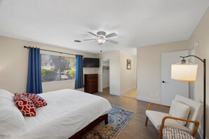 Une chambre à coucher avec un lit, un ventilateur de plafond, une commode, un téléviseur et une lampe.
