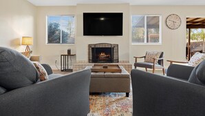 A living room with a fireplace, a flat-screen TV, and two grey sofas. - Las Vegas Oasis with Private Pool and Hot Tub 12-min from The Strip (Las Vegas)