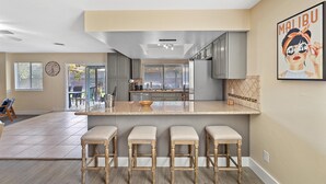 A modern kitchen with a central island, bar stools, and a large window. - Las Vegas Oasis with Private Pool and Hot Tub 12-min from The Strip (Las Vegas)
