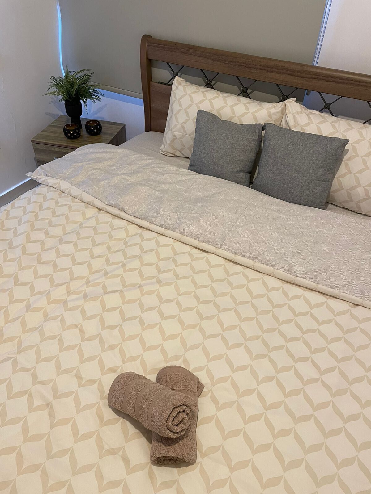 Un lit bien fait, avec une couvre-lit à motifs, deux oreillers et une serviette enroulée posée sur le lit.