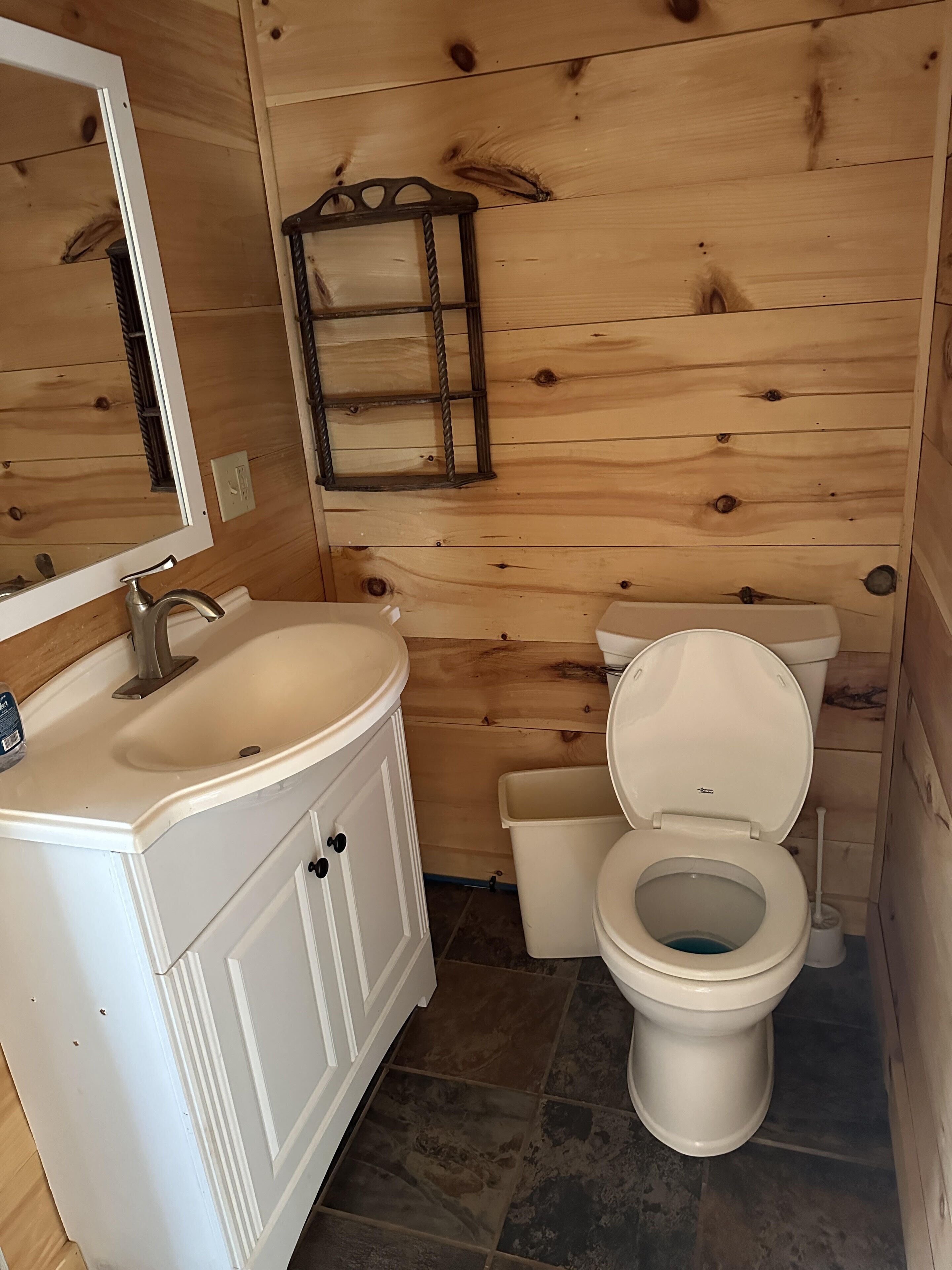 A bathroom with wooden walls, a white sink, and a toilet.