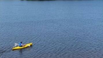 Deux kayaks sur un lac paisible, bordé d’une rive boisée.