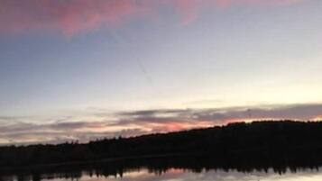 Un lac paisible au crépuscule, bordé d’une forêt et surplombé d’un ciel dégagé.