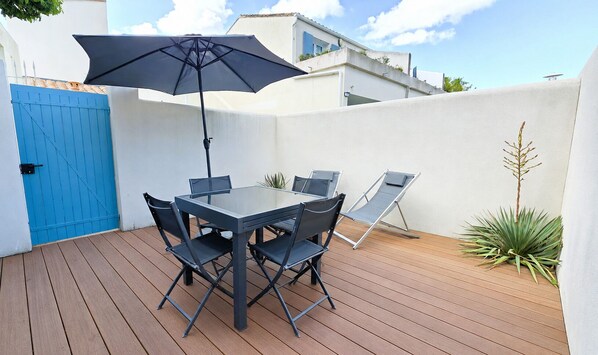 An outdoor patio with a table and chairs, a blue gate, and a potted plant. - AGATHE (2 route de St Martin, La Flotte) (La Flotte)