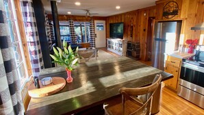 Un interior de madera con una mesa de comedor, sillas, un refrigerador y un televisor.