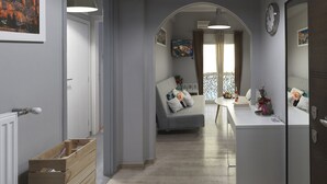 Um interior moderno com um corredor que leva a uma sala de estar com sofá, mesa de jantar e cozinha.