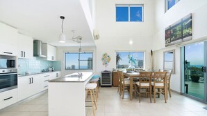 A modern kitchen with white cabinets, a central island, and a dining area with wooden chairs.
