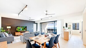 Un soggiorno moderno con divano, TV e zona pranzo con sedie e tavolo.