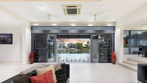 A modern hotel lobby with a black leather sofa, a glass entrance, and a view of a building across a water body.