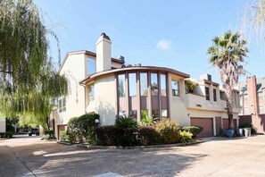 Stunning residential building with a curved facade, multiple windows, and a chimney, set amidst beautifully maintained landscaping.