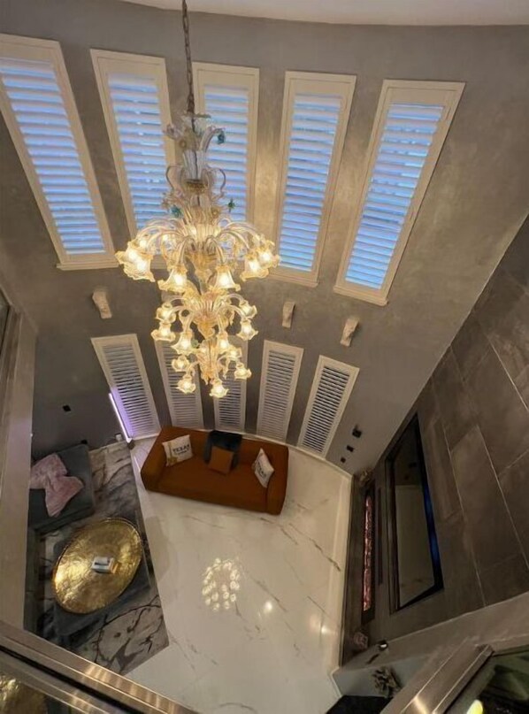 Relax in this spacious room with a high ceiling, skylights, and a chandelier. Enjoy a dining or kitchen area with a marble countertop, seating for relaxation, and a large flat-screen TV.
