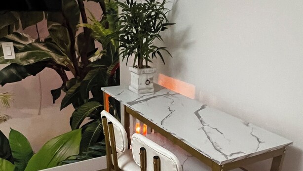 Un pequeño espacio de cocina moderno con encimera de mármol, dos taburetes de bar y una planta en maceta.