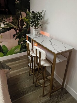 Un pequeño espacio de cocina moderno con encimera de mármol, dos taburetes de bar y una planta en maceta.