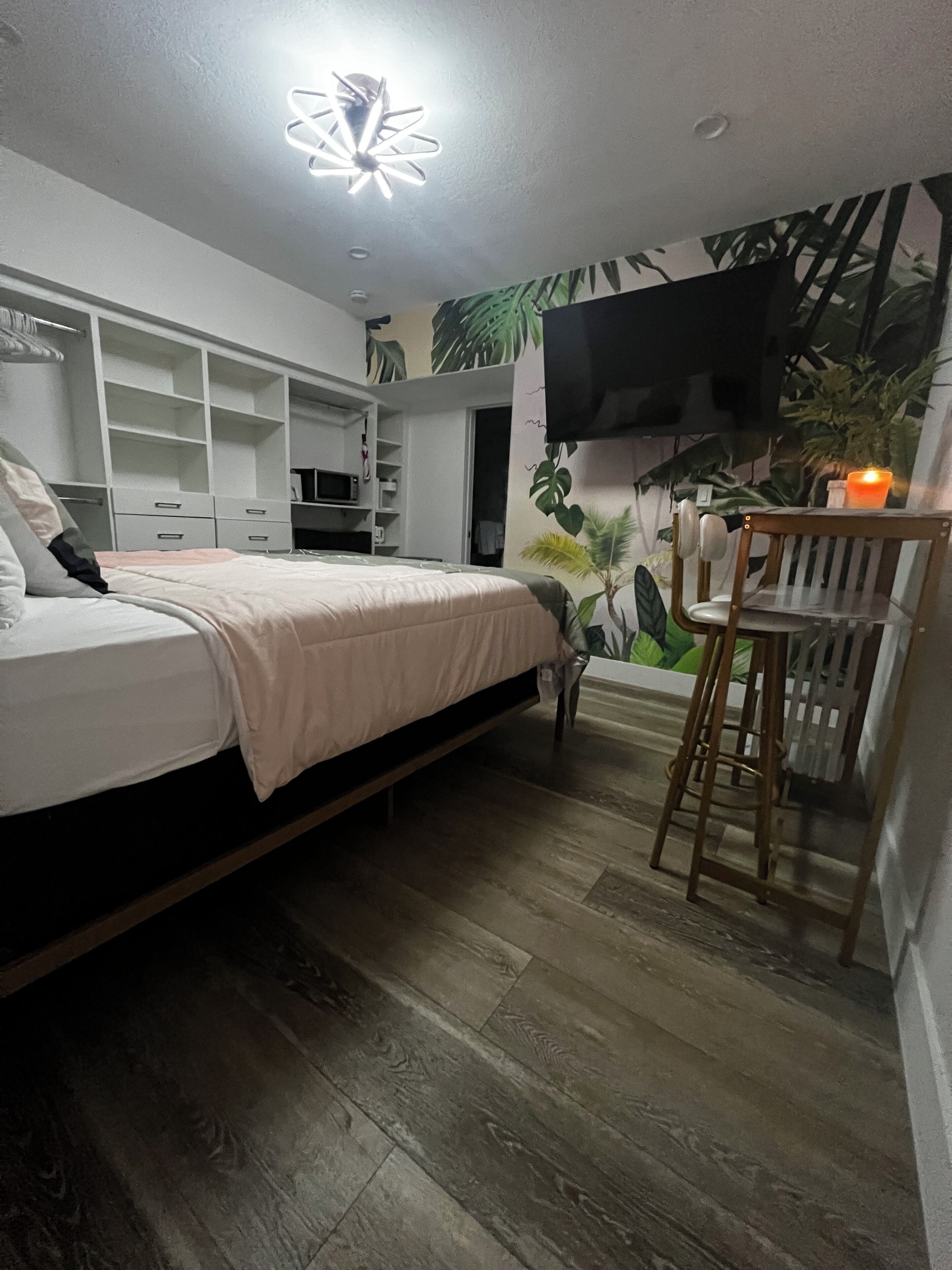 A bedroom with a bed, a TV, a desk, and a chair.