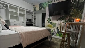 Un dormitorio con cama, televisor, escritorio y silla.