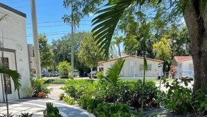 Un sendero curvo que conduce a un edificio de diseño moderno, rodeado de abundante vegetación y diversas plantas.