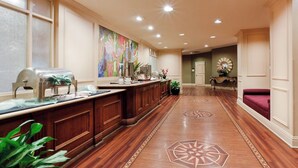 A long reception area with a wooden counter, a colorful painting, and a patterned floor. - Reading Vitality Hotel (Wyomissing)