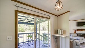 A room with a sliding glass door leading to an outdoor deck, a small white table, a green chair, and a sofa with a leopard print cover. - Fire Pit + Deck: Peaceful Silver Creek Retreat (Silver Creek)