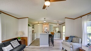A spacious living area with a sofa, a patterned armchair, and a kitchen in the background. - Fire Pit + Deck: Peaceful Silver Creek Retreat (Silver Creek)