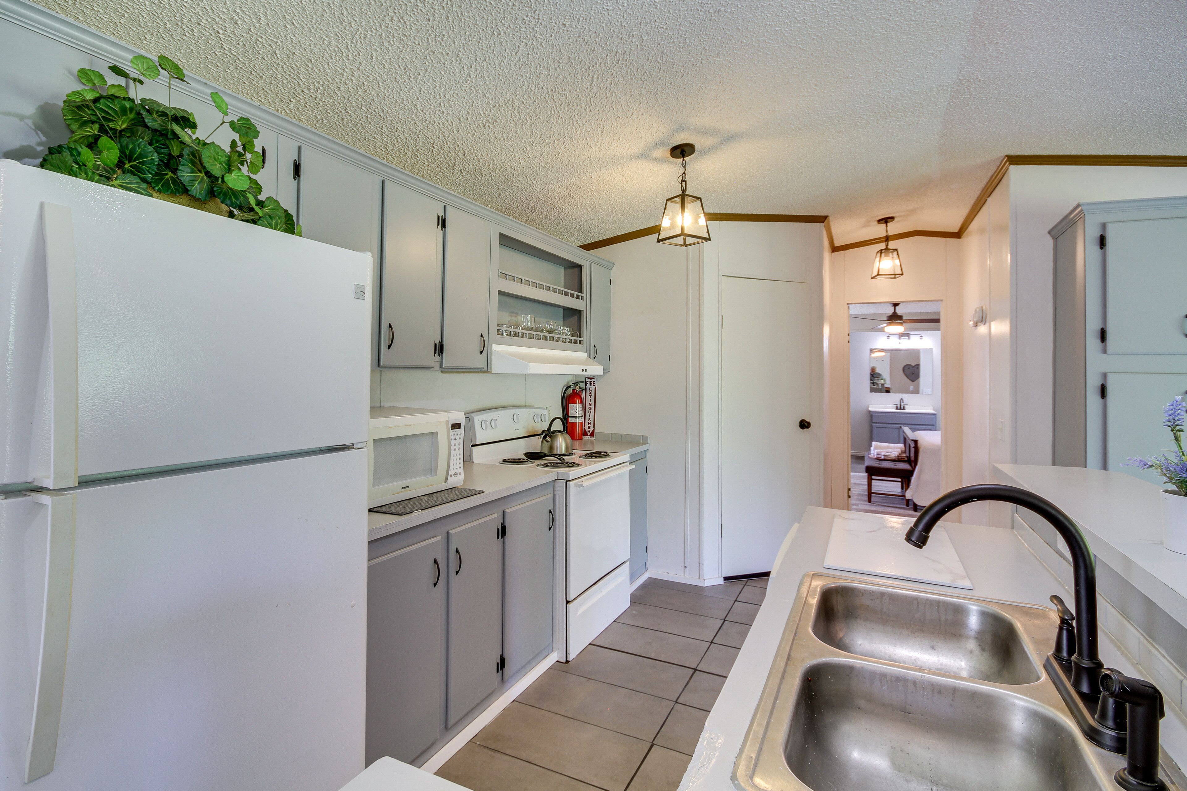 A kitchen with white cabinets, a stove, a microwave, and a sink.