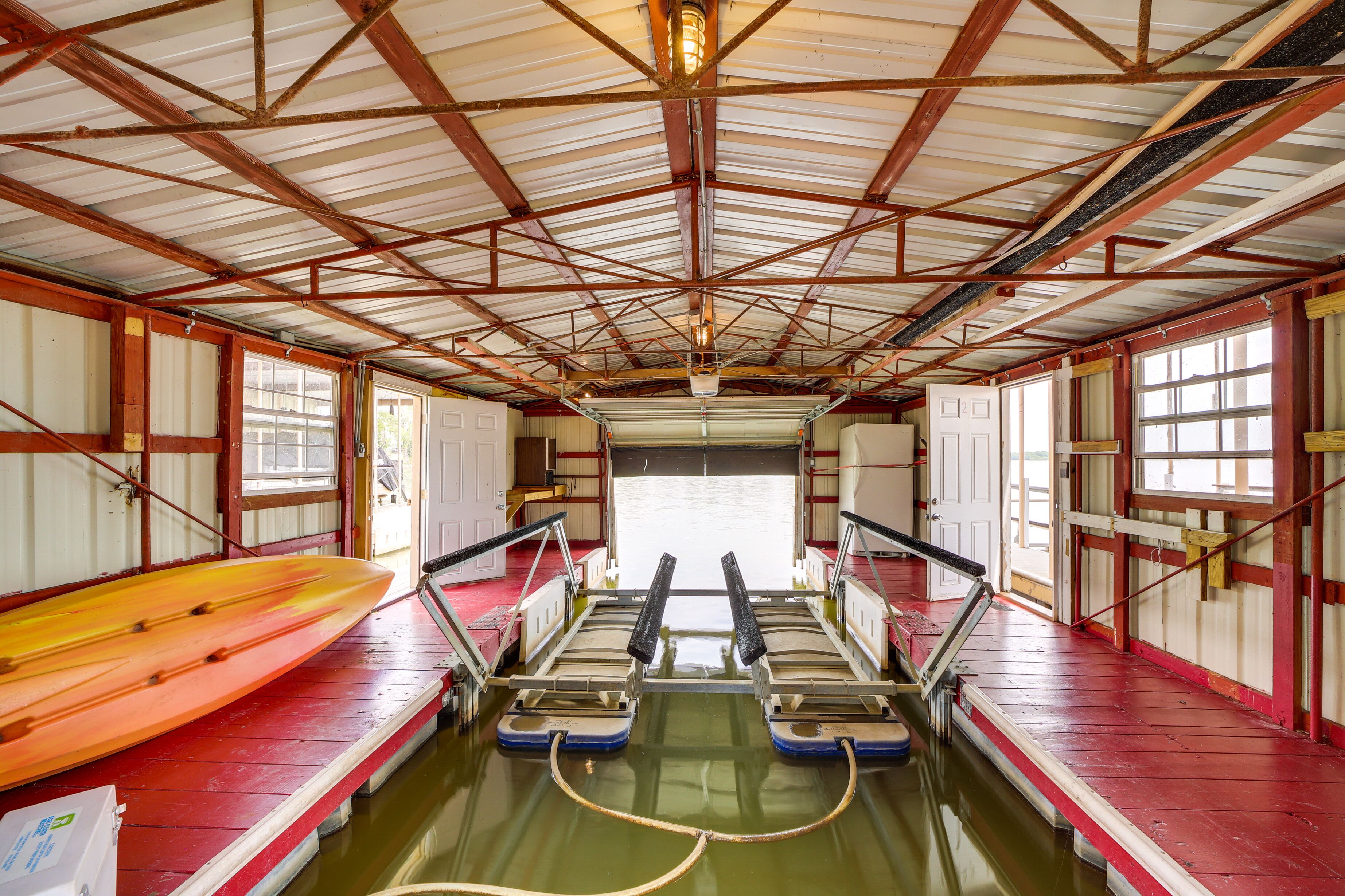 Interior de un barco con techo metálico, ventanas y un kayak a la izquierda.