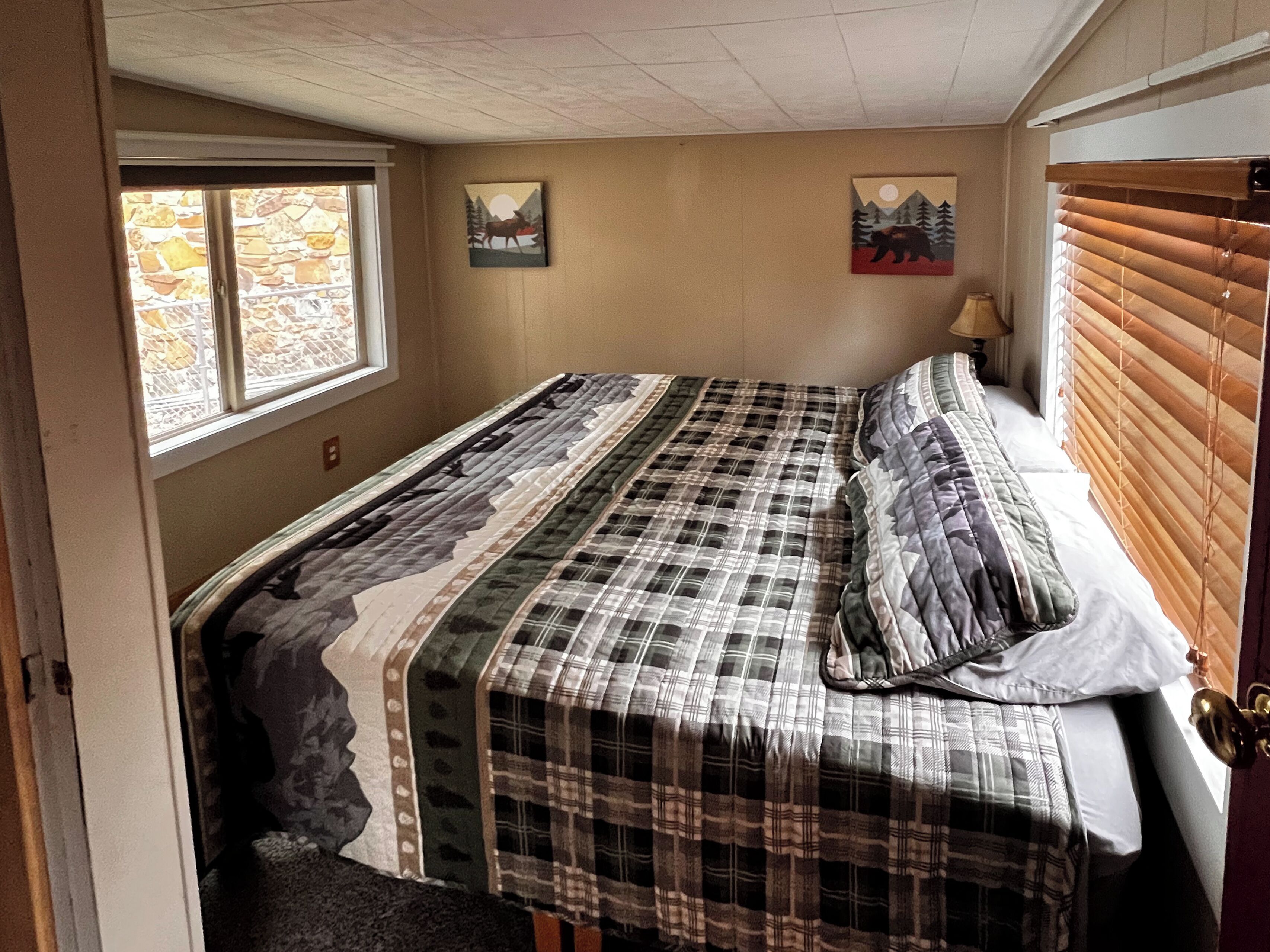 Een slaapkamer met een bed, een raam en twee kunstwerken aan de muur.