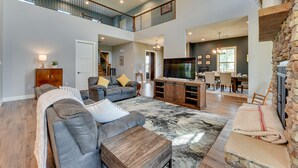 A spacious living area with a large sectional sofa, a wooden coffee table, and a stone fireplace. - Spacious Lake Charles Craftsman - Pet Friendly! (Lake Charles)