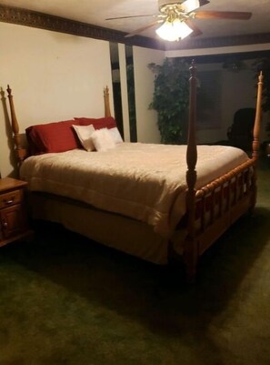 A four-poster bed with a wooden frame, a red headboard, and a beige bedspread. - Castle Cove Lakefront Home (Goreville)