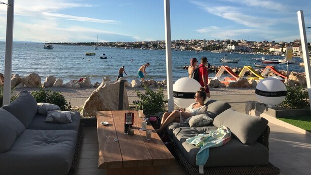 A lounge area with outdoor seating, a view of the sea, and a distant town. - Apartment Oleander - One Bedroom Apt with Terrace (Novalja)