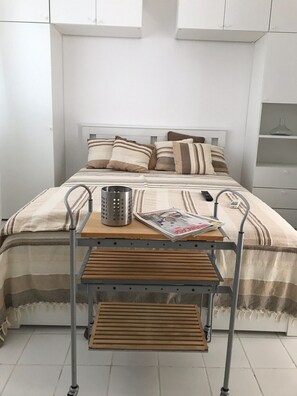 A neatly made bed with striped bedding, a bedside table with a magazine, and a small metal container. - Apartment Oleander - One Bedroom Apt with Terrace (Novalja)