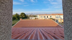 Uitzicht vanaf een balkon met een terrasdak, uitkijkend op een woonwijk met huizen en groen.
