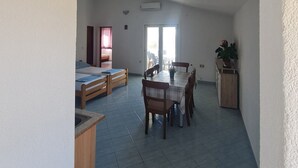 A spacious living area with a dining table, chairs, a sofa, and a small kitchen area.